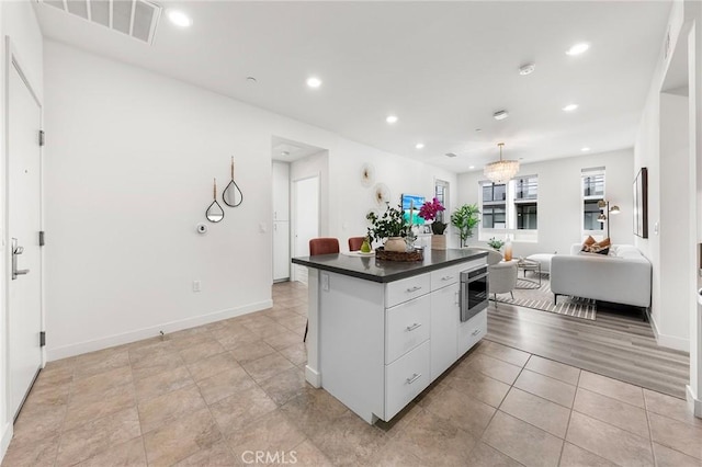 2526 Nolita, Irvine, CA 92612 - kitchen featuring dark countertops, a kitchen island, recessed lighting, open floor plan, and white cabinetry