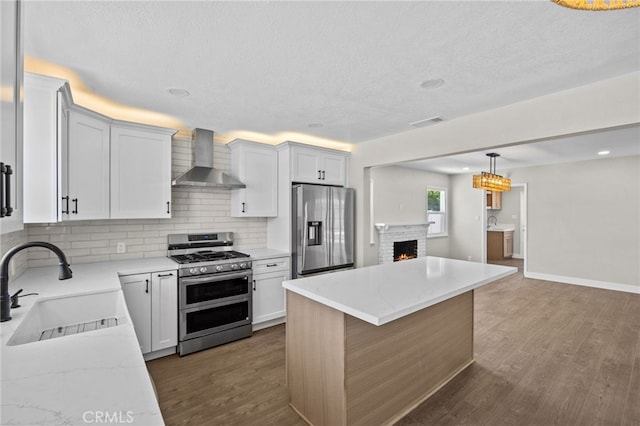 1514 E Palm Ave, Orange, CA 92866 - kitchen with stainless steel appliances, wall chimney range hood, tasteful backsplash, dark wood-style flooring, and a brick fireplace