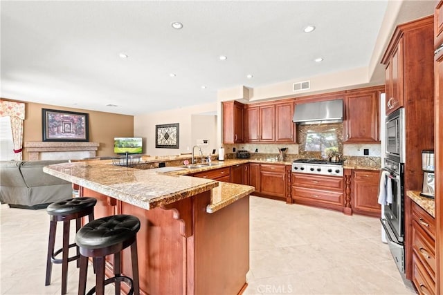 31148 Kahwea Rd, Temecula, CA 92591 - kitchen with wall chimney range hood, stainless steel appliances, a peninsula, open floor plan, and a breakfast bar