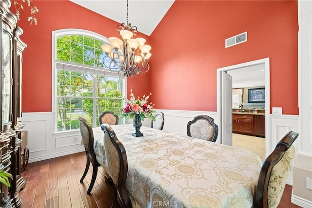 31148 Kahwea Rd, Temecula, CA 92591 - dining area with a chandelier, high vaulted ceiling, wood finished floors, a wainscoted wall, and a decorative wall
