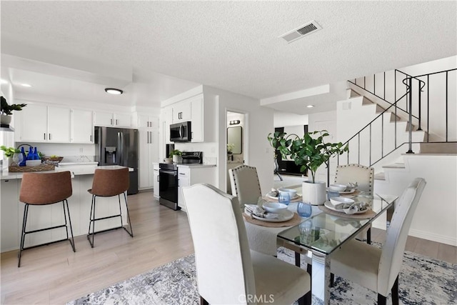 11338 Grand Manan Dr, Cypress, CA 90630 - dining room with light wood-type flooring, a textured ceiling, stairs, and recessed lighting