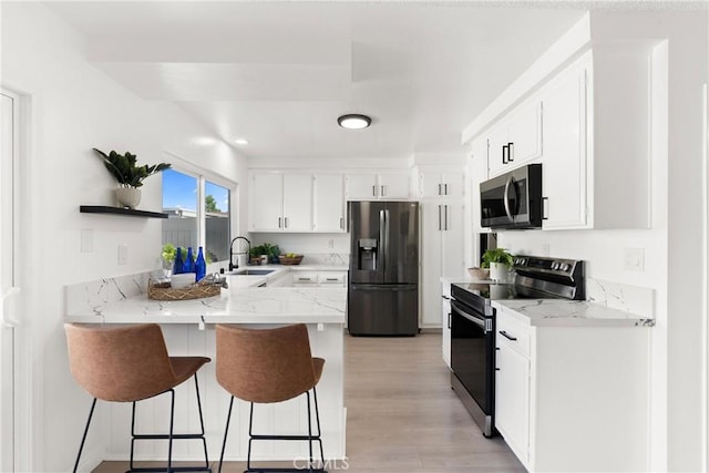11338 Grand Manan Dr, Cypress, CA 90630 - kitchen featuring stainless steel appliances, a peninsula, light stone counters, light wood finished floors, and a kitchen breakfast bar
