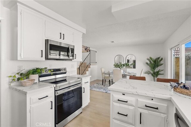 11338 Grand Manan Dr, Cypress, CA 90630 - kitchen featuring appliances with stainless steel finishes, light wood finished floors, white cabinetry, and light stone countertops