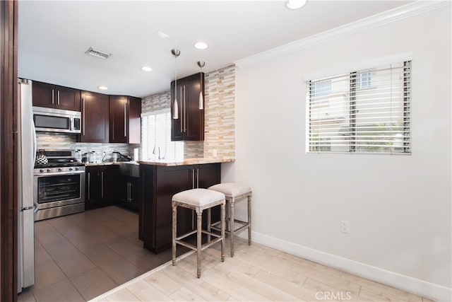 13632 Valerio St Unit 2, Van Nuys, CA 91405 - kitchen featuring stainless steel appliances, decorative backsplash, a breakfast bar, crown molding, and dark brown cabinets
