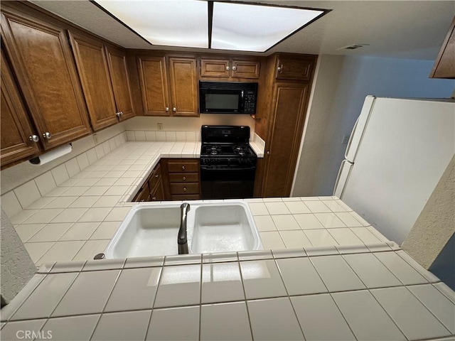 600 Central Ave Unit 323, Riverside, CA 92507 - kitchen with black appliances, tile countertops, and brown cabinets
