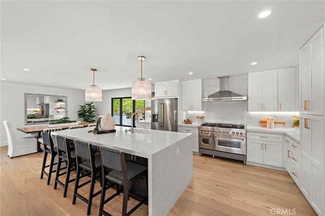 31842 Paseo Cielo, San Juan Capistrano, CA 92675 - kitchen with wall chimney range hood, premium appliances, light wood-style flooring, backsplash, and recessed lighting