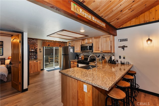 721 Riverside Ave, Sugarloaf, CA 92386 - kitchen featuring stainless steel appliances, lofted ceiling, light wood-type flooring, a kitchen bar, and light stone countertops