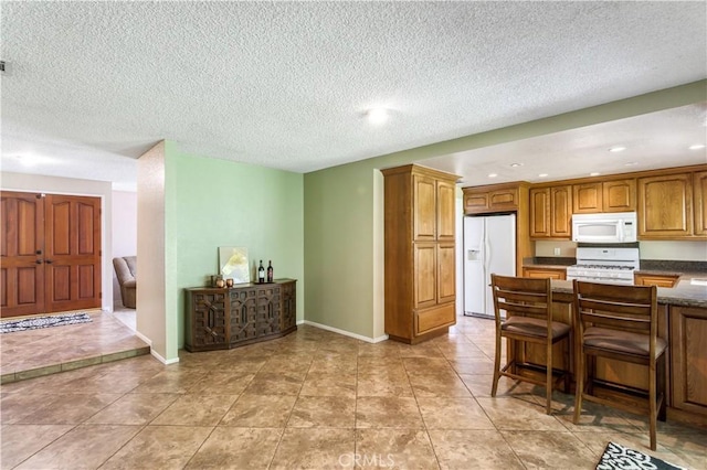 5731 Camino Real, Riverside, CA 92509 - kitchen with white appliances, brown cabinetry, a kitchen breakfast bar, dark countertops, and recessed lighting
