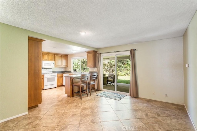 5731 Camino Real, Riverside, CA 92509 - kitchen with white appliances, a kitchen bar, a textured ceiling, a peninsula, and light countertops