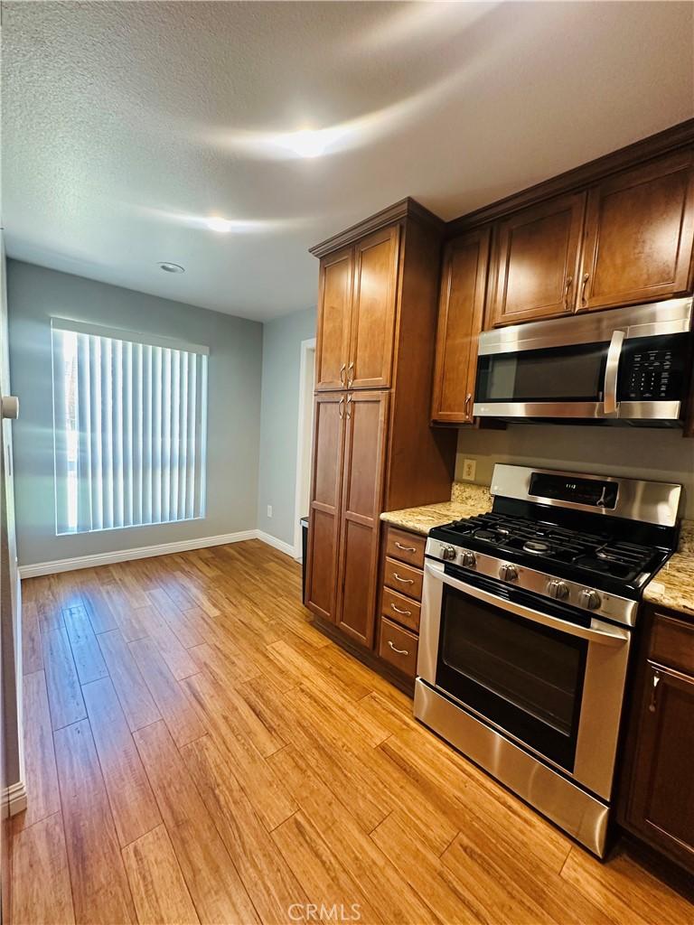 4674 Maxwell Ct, Riverside, CA 92501 - kitchen featuring stainless steel appliances, light wood-type flooring, and light stone counters