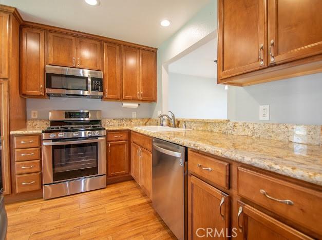 4674 Maxwell Ct, Riverside, CA 92501 - kitchen with appliances with stainless steel finishes, brown cabinetry, light wood-type flooring, light stone countertops, and recessed lighting