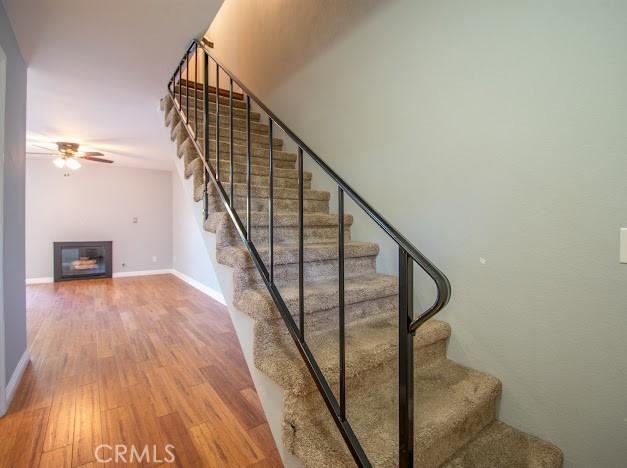 4674 Maxwell Ct, Riverside, CA 92501 - stairway with wood finished floors, ceiling fan, and a glass covered fireplace