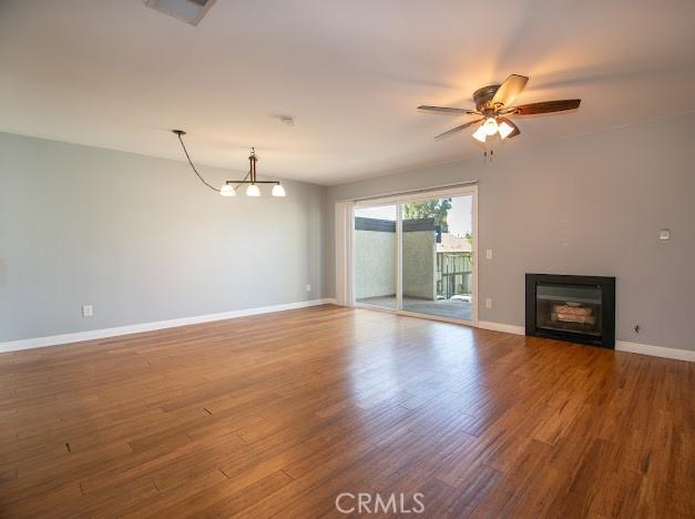 4674 Maxwell Ct, Riverside, CA 92501 - unfurnished living room with a glass covered fireplace, wood finished floors, a ceiling fan, and a chandelier