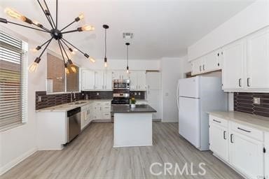 38742 Berrycreek Ct, Palmdale, CA 93551 - kitchen featuring stainless steel appliances, a chandelier, decorative backsplash, and white cabinetry