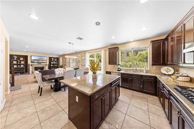 6585 Youngstown St, Chino, CA 91710 - kitchen with light stone countertops, a fireplace, dark brown cabinets, tasteful backsplash, and recessed lighting