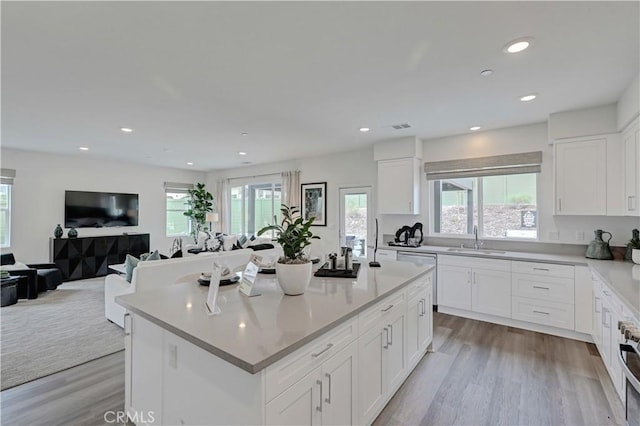 17148 Kent St, Hesperia, CA 92345 - kitchen with healthy amount of natural light, a kitchen island, light wood-style floors, white cabinets, and recessed lighting