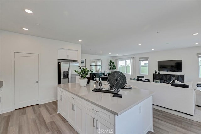 17148 Kent St, Hesperia, CA 92345 - kitchen with stainless steel refrigerator with ice dispenser, light wood-style flooring, white cabinetry, a center island, and open floor plan