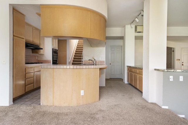 2532 Navarra Dr Unit A, Carlsbad, CA 92009 - kitchen featuring light carpet, a peninsula, under cabinet range hood, tile counters, and decorative backsplash