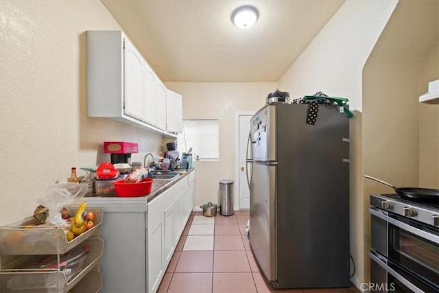 1148 E 43rd, Los Angeles, CA 90011 - kitchen with stainless steel appliances, white cabinets, light tile patterned floors, and light countertops