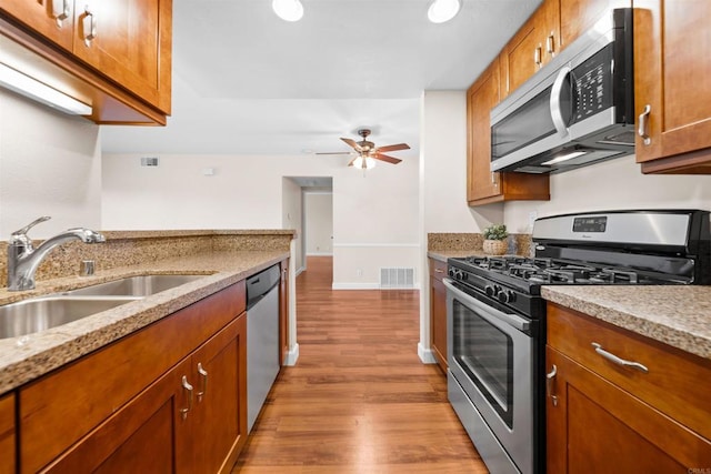 1087 Shadowridge Dr Unit 101, Vista, CA 92081 - kitchen with stainless steel appliances, wood finished floors, brown cabinets, light stone countertops, and a ceiling fan