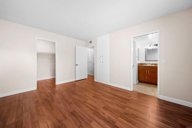 1087 Shadowridge Dr Unit 101, Vista, CA 92081 - unfurnished bedroom featuring wood finished floors, a closet, ensuite bath, and a walk in closet