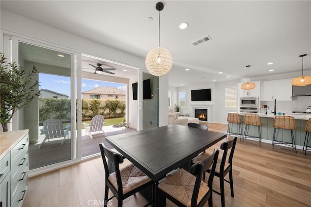 32067 Dawning Rdg, Temecula, CA 92591 - dining space with light wood finished floors, recessed lighting, ceiling fan, and a warm lit fireplace