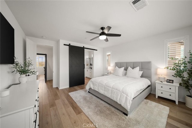 32067 Dawning Rdg, Temecula, CA 92591 - bedroom featuring a barn door, light wood-style flooring, a ceiling fan, and connected bathroom
