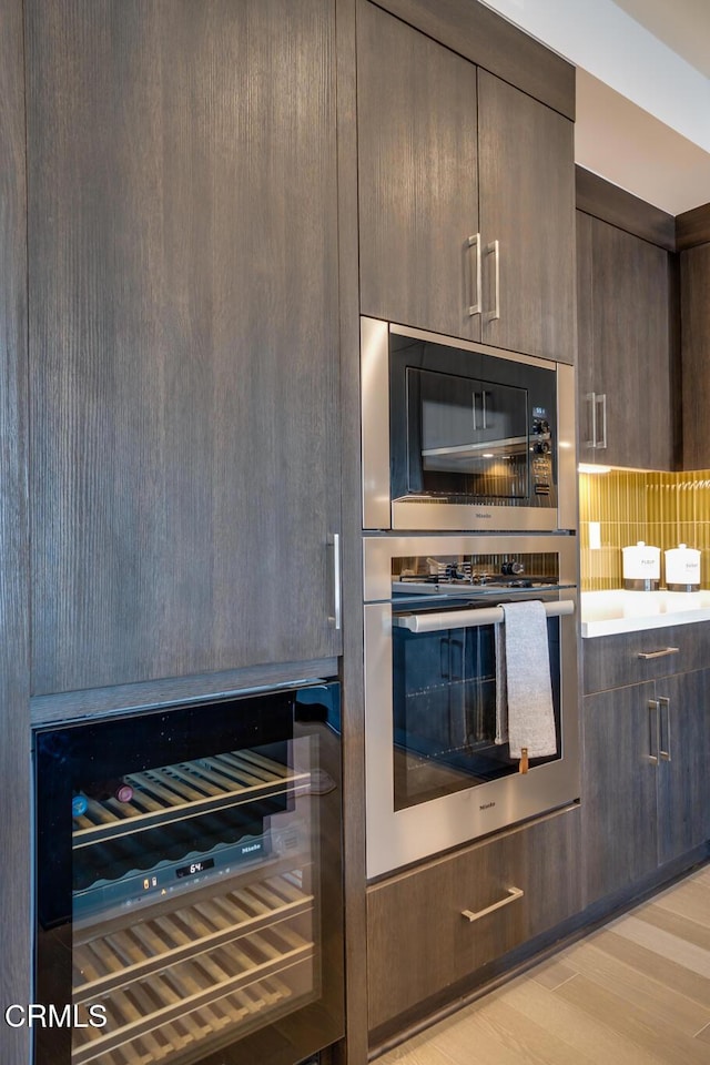 820 Mission St Unit 208, South Pasadena, CA 91030 - kitchen featuring black microwave, beverage cooler, tasteful backsplash, dark brown cabinets, and light wood finished floors