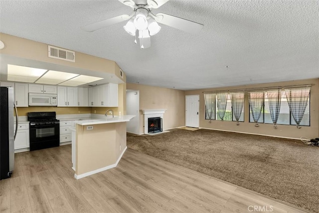43195 Andrade Ave Unit K, Hemet, CA 92544 - kitchen featuring black gas range, white microwave, a textured ceiling, open floor plan, and freestanding refrigerator