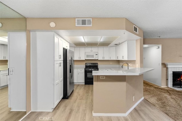 43195 Andrade Ave Unit K, Hemet, CA 92544 - kitchen featuring black range with gas cooktop, white microwave, stainless steel refrigerator with ice dispenser, a peninsula, and light wood finished floors