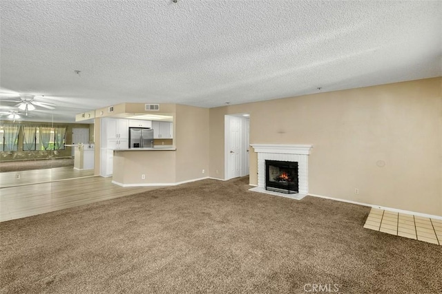 43195 Andrade Ave Unit K, Hemet, CA 92544 - unfurnished living room featuring carpet flooring, a brick fireplace, ceiling fan, and a textured ceiling