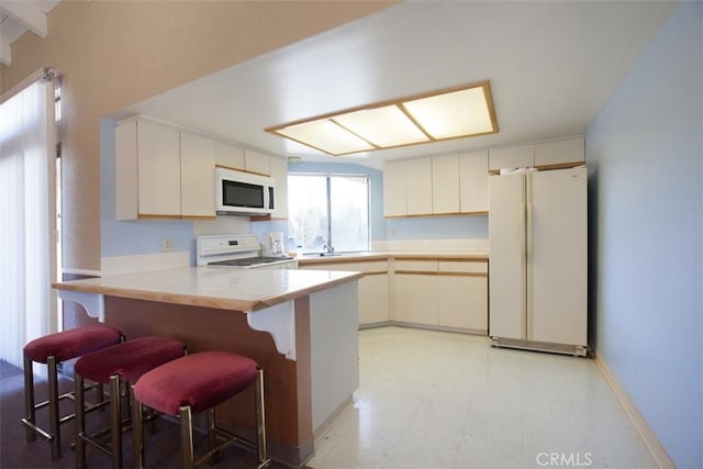 43195 Andrade Ave Unit K, Hemet, CA 92544 - kitchen with white appliances, light floors, a peninsula, light countertops, and a breakfast bar