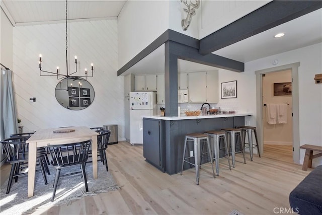 362 Old Mammoth Rd Unit 47, Mammoth Lakes, CA 93546 - kitchen with freestanding refrigerator, a towering ceiling, a chandelier, light wood-type flooring, and a peninsula