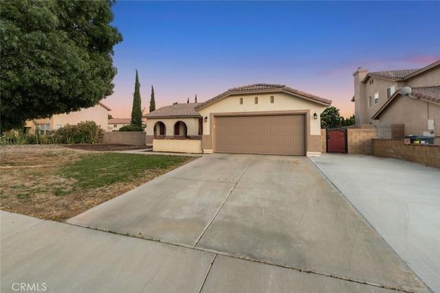 1706 Regents St, Lancaster, CA 93534 - mediterranean / spanish-style house with a gate, concrete driveway, a garage, stucco siding, and a tile roof
