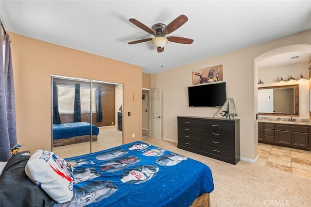 1706 Regents St, Lancaster, CA 93534 - bedroom with arched walkways, light carpet, a closet, connected bathroom, and ceiling fan