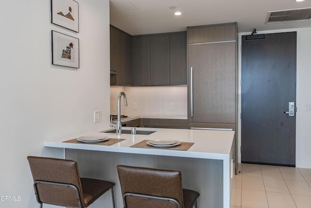 889 Francisco St Unit 802, Los Angeles, CA 90017 - kitchen featuring a kitchen bar, a peninsula, light countertops, light tile patterned floors, and modern cabinets