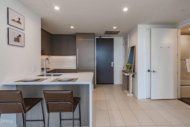 889 Francisco St Unit 802, Los Angeles, CA 90017 - kitchen featuring modern cabinets, a kitchen bar, light countertops, dark brown cabinets, and a peninsula