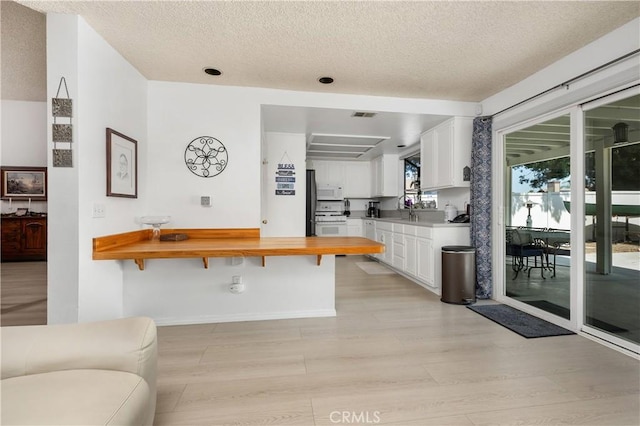 1365 Kroonen Dr, Corona, CA 92882 - kitchen featuring stove, butcher block countertops, white cabinetry, light wood finished floors, and a textured ceiling