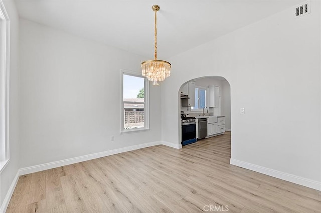12887 Mount Vernon Ave, Grand Terrace, CA 92313 - unfurnished dining area with light wood-style flooring, arched walkways, and a chandelier