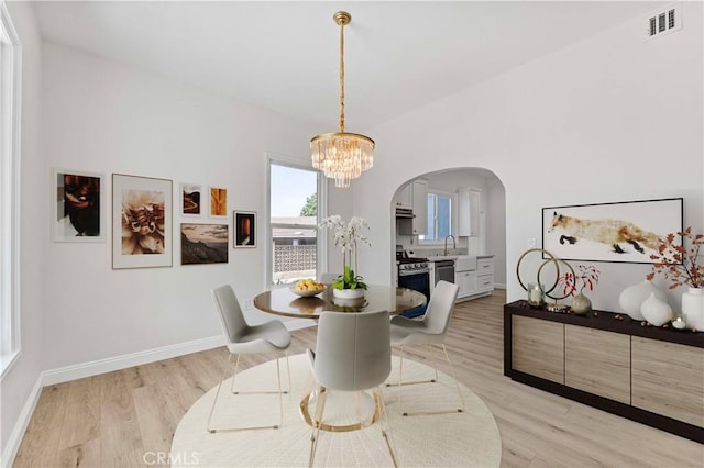 12887 Mount Vernon Ave, Grand Terrace, CA 92313 - dining area featuring arched walkways, a chandelier, and light wood finished floors