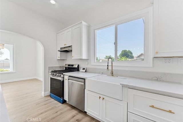 12887 Mount Vernon Ave, Grand Terrace, CA 92313 - kitchen featuring appliances with stainless steel finishes, under cabinet range hood, white cabinetry, light wood-type flooring, and light stone countertops