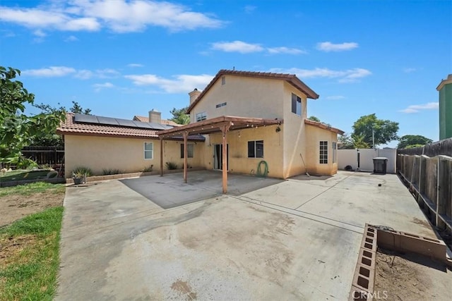 13969 Chervil Ct, Moreno Valley, CA 92553 - rear view of house featuring roof mounted solar panels, a patio, a fenced backyard, stucco siding, and a tile roof