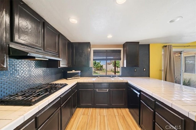 13969 Chervil Ct, Moreno Valley, CA 92553 - kitchen featuring black appliances, tile countertops, under cabinet range hood, light wood finished floors, and tasteful backsplash