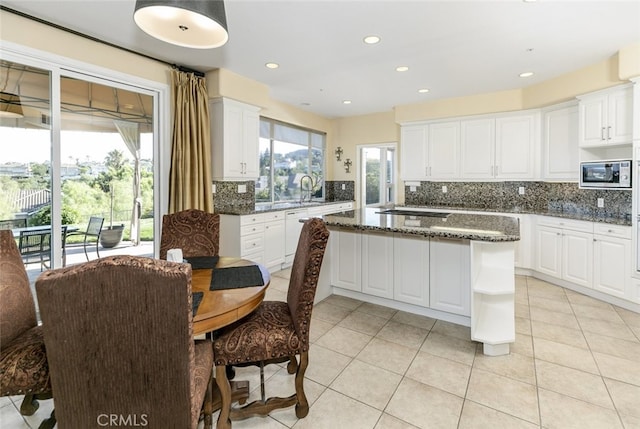 24736 Wooded Vis, West Hills, CA 91307 - kitchen with stainless steel microwave, tasteful backsplash, a kitchen island, white cabinetry, and light tile patterned flooring