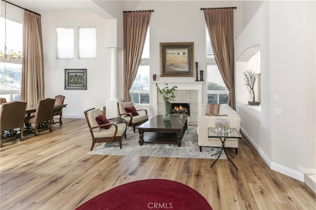 24736 Wooded Vis, West Hills, CA 91307 - living area with a tiled fireplace, a chandelier, wood finished floors, decorative columns, and a towering ceiling