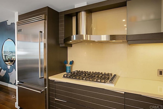 1325 Pacific Hwy Unit 2106, San Diego, CA 92101 - kitchen featuring appliances with stainless steel finishes, wall chimney range hood, dark brown cabinetry, light countertops, and dark wood finished floors