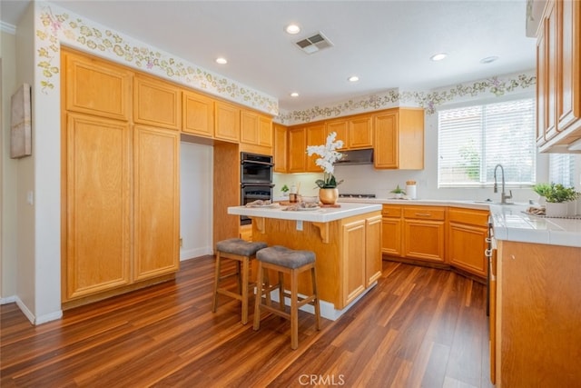 4892 Borders St, Simi Valley, CA 93063 - kitchen with dark wood finished floors, a kitchen bar, a center island, recessed lighting, and tile countertops