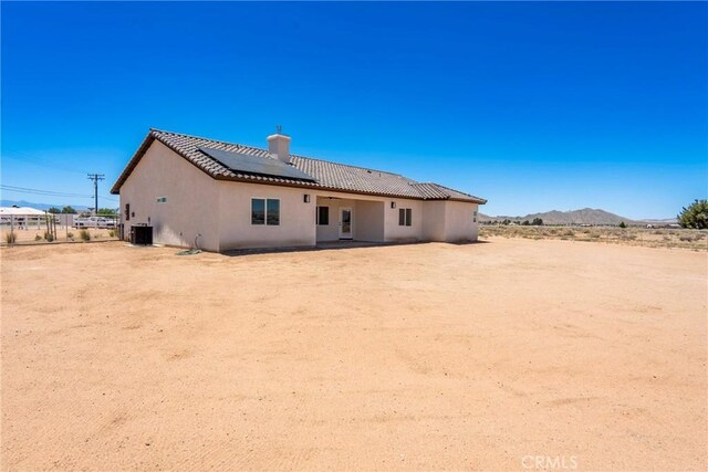 15323 Turquoise Rd, Apple Valley, CA 92307 - back of house with solar panels, a chimney, stucco siding, a tile roof, and a mountain view