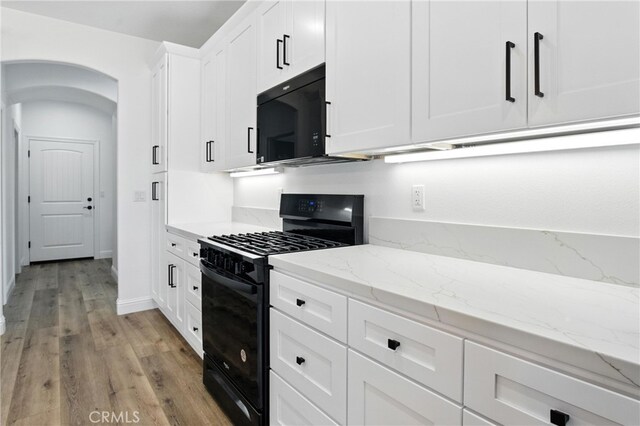 15323 Turquoise Rd, Apple Valley, CA 92307 - kitchen with black appliances, arched walkways, light wood finished floors, white cabinets, and light stone counters