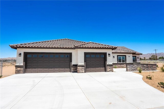 15323 Turquoise Rd, Apple Valley, CA 92307 - mediterranean / spanish home featuring stone siding, driveway, an attached garage, and stucco siding